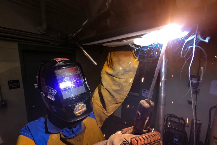 Welder striking an arc behind a shielded helmet